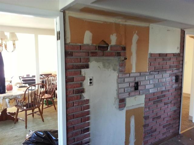 89:  This is the kitchen side with the six linear feet of cabinet and countertop removed. The base cabinets are temporarily moved to the exterior kitchen wall. The uppers will be repurposed in the basement or the garage, if I can get them sturdy again. You can see the outline of the fridge and cabinets in the brick facade.
