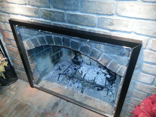 165: We had to fabricate a rectangular frame out of 1-1/4 inch square steel tubing.  We drilled and bolted the frame into the brick. Then we cut and painted aluminum L stock as trim.  All this lets us mount the fireplace doors against the arched opening that otherwise wouldn't accomodate them.