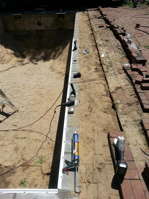 256: The aluminum liner track starts going in.  We used liquid nails between the track and the concrete block, then we sunk in masonry screws every 8 inches.  Finally put that hammer drill to good use, and I'm proud to sya I didnt break a single bit this time.