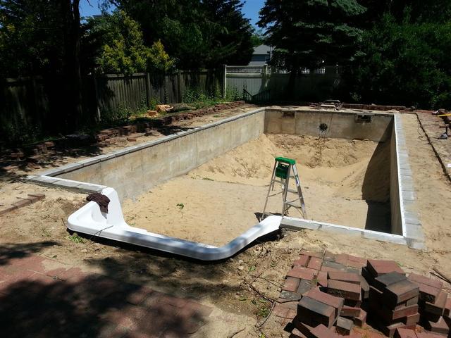 257: All the liner track is in place.  Its not very straight, both side to side, as well as vertically, thanks to my very poor job laying teh concrete block.  I did my best to shim the track using miscelaneous pennies, nickles and dimes, but there is still a bit of visable runout.  Im going to have to do a bangup job on the coping to try and redeem myself and make things look a little more straight.