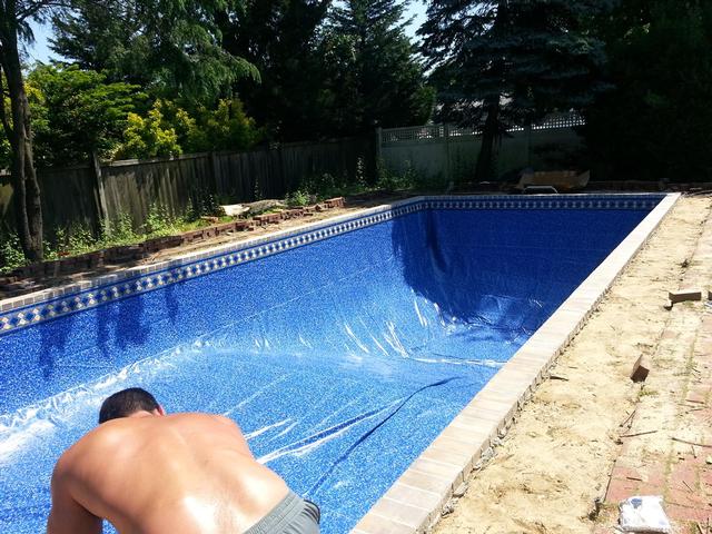 276: With six guys (including my wife), it was relatively easy to pull the liner over the pool.  It took some persuasion to get it into position, but we finally got it in place as best we could.  The corners are particularly difficult, since theres no way to actually get the liner bead into the track at the 90 degree angle.