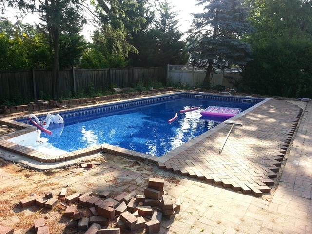 285: With another sand delivery, we were able to grade and reseat some more pavers along the pool.  We also poured the concrete collar around the lip of the stairs, and we test fit the coping pavers around the stairs dry before more rain threatened.